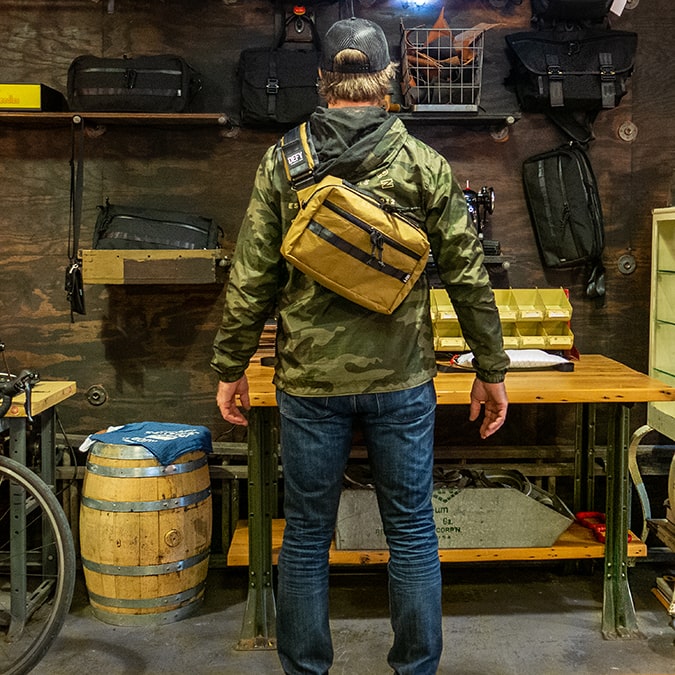 A man modeling the Insidious Jr sling bag made by DEFY