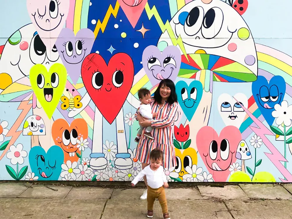 A mother poses with her children in front of Chris Uphues' Happy Garage mural along Ravenswood Ave